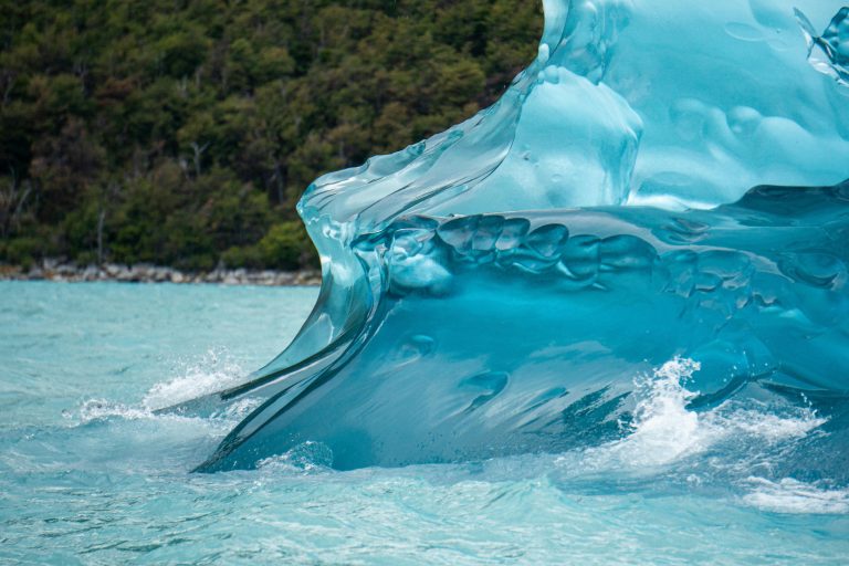 Captivating shot of a beautifully carved iceberg in vibrant blue water, showcasing natural ice formations.