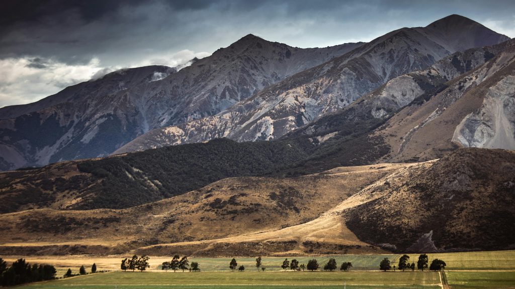 Explore the breathtaking mountain landscape of New Zealand featuring rugged peaks and lush valleys.